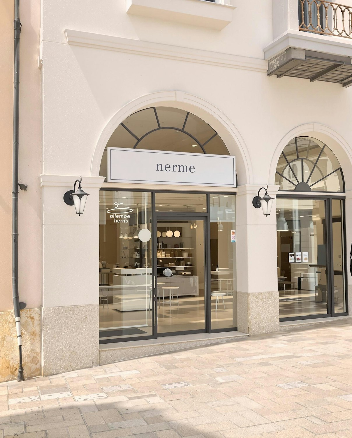 Cream shopfront with tall arched windows and a softly lit interior