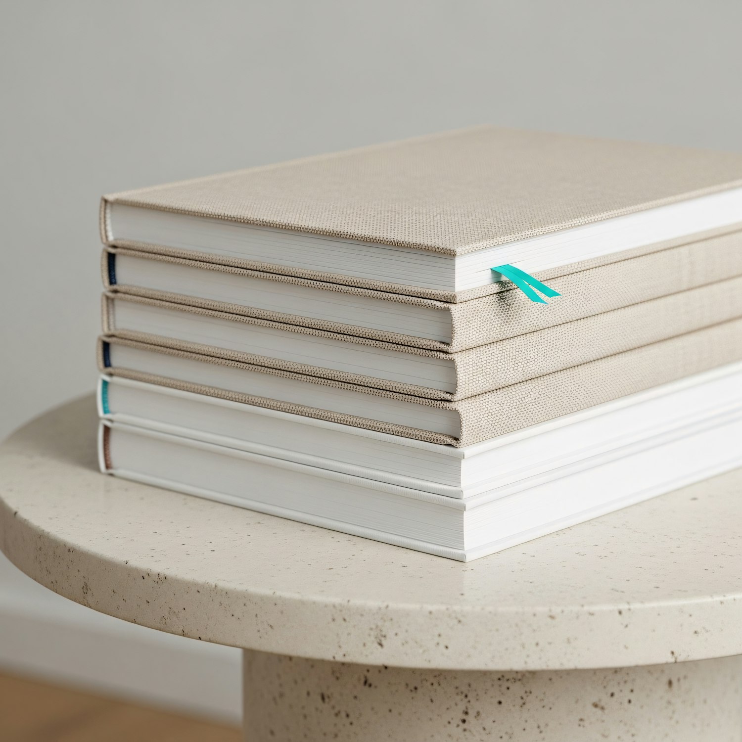 Stack of beige hardcover books with a turquoise ribbon bookmark